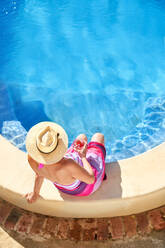 View from above senior woman relaxing at sunny summer swimming pool - CAIF33871