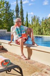 Senior man relaxing at sunny summer swimming pool - CAIF33876