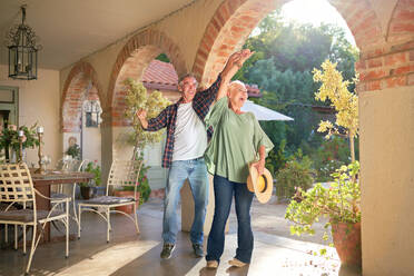 Happy, carefree senior couple dancing on sunny villa patio - CAIF33883