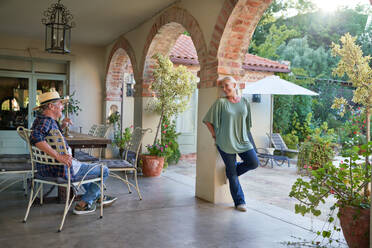 Happy senior couple talking on summer villa patio - CAIF33888