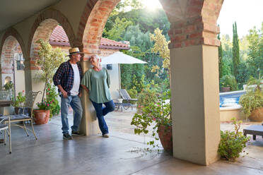 Senior couple talking on summer villa patio - CAIF33889