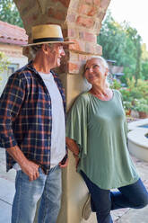 Happy senior couple talking on patio - CAIF33890