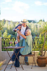 Happy senior couple video chatting on summer balcony - CAIF33895