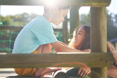 Happy sister and brother with Down Syndrome at top of sunny slide - CAIF33915