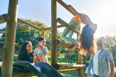 Happy family playing at playground equipment in sunny backyard - CAIF33920