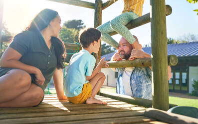 Happy family playing at playground structure in sunny park - CAIF33922