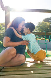 Happy mother and son at sunny playground structure - CAIF33923