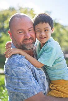 Portrait smiling father holding cute son with Down Syndrome - CAIF33942