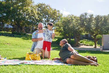 Happy family relaxing and playing with bubbles in sunny summer park - CAIF33952