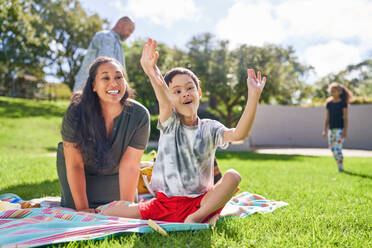 Happy mother watching cute son with Down Syndrome eating in park - CAIF33955