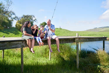 Family with binoculars fishing on pier at summer lakeside - CAIF33971