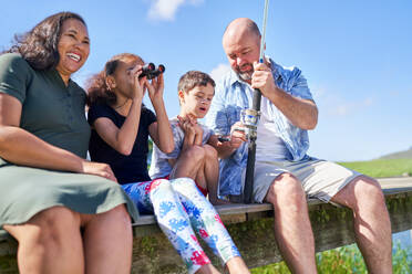 Happy family with binoculars fishing on summer pier - CAIF33972