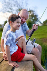 Sea bridge father sons fishing rod-equipment cheerfully autumn series  people man 30-40 years children two boys 11-13 years Stock Photo - Alamy