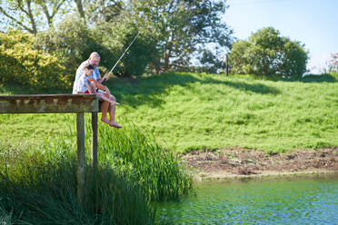 Father and son fishing on sunny summer lakeside dock - CAIF33978