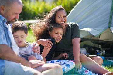 Portrait happy family hugging outside tent at summer campsite - CAIF33984