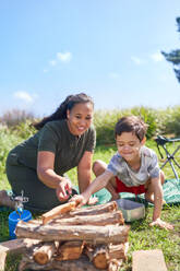 Mother and son with Down Syndrome stacking firewood at campsite - CAIF33985