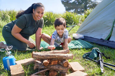 Mother and son with Down Syndrome stacking firewood at campsite - CAIF33986