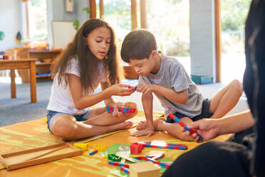 Sister and brother with Down Syndrome playing with toys on floor - CAIF33995