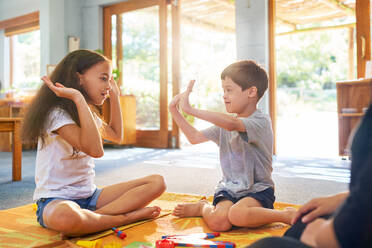 Sister playing clapping game with brother with Down Syndrome at home - CAIF33998