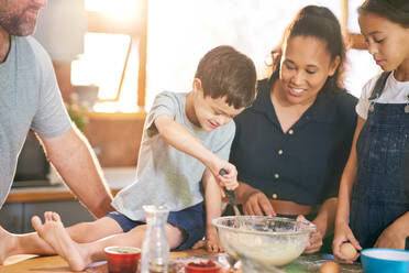 Happy boy with Down Syndrome baking with family in kitchen - CAIF34008