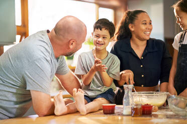 Happy boy with Down Syndrome baking with family in kitchen at home - CAIF34009