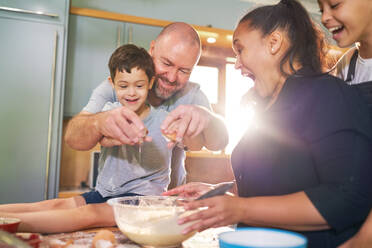 Happy boy with Down Syndrome baking with family in kitchen - CAIF34011
