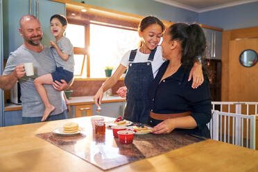 Happy family eating pancakes in morning kitchen - CAIF34016