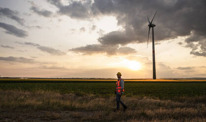 Engineer on wind field in front of sunset sky - UUF29273