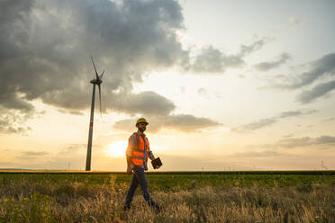 Ingenieur mit Tablet-PC beim Spaziergang im Windpark - UUF29280