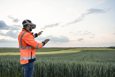 Engineer wearing virtual reality headset in field - UUF29301