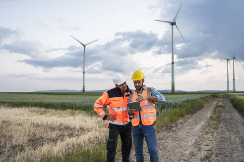 Ingenieure arbeiten mit Tablet-PC im Windpark zusammen - UUF29310