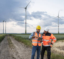 Engineers working together with tablet computer at wind farm - UUF29311