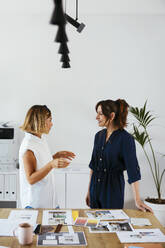 Colleagues discussing at desk in creative office - EBSF03655