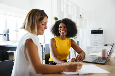 Glückliche Geschäftsfrauen arbeiten am Schreibtisch in einem kreativen Büro - EBSF03663