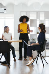 Businesswoman discussing with colleagues in meeting at creative office - EBSF03665