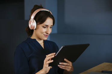 Geschäftsfrau mit Kopfhörern und Tablet-PC im Kreativbüro - EBSF03669