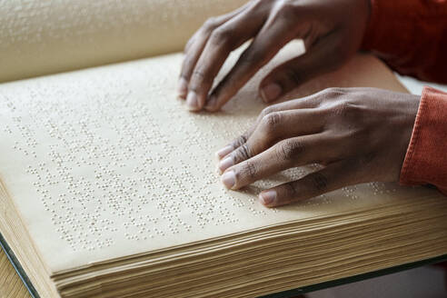 Hands of woman reading braille text from book - AAZF00768