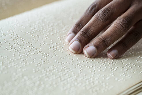 Woman reading braille text on page from book - AAZF00772