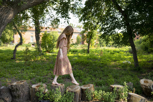 Young woman walking on tree stumps - TETF01992