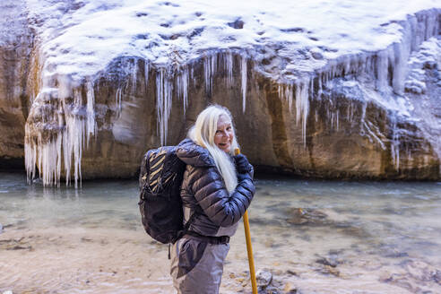 USA, Utah, Springdale, Zion National Park, Senior woman crossing river while hiking in mountains - TETF02000