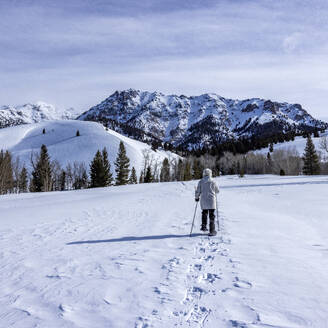 USA, Idaho, Sun Valley, Senior woman wearing snowshoes hiking in mountains - TETF02020