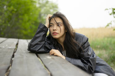 Portrait of teenage girl (16-17) leaning on picnic table - TETF02040