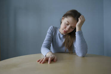 Portrait of tired woman sitting at round table at home - TETF02044