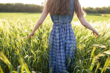 Rear view of woman walking in field - TETF02046