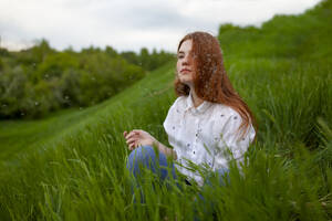 Portrait of serious teenage girl (16-17) sitting on grass - TETF02049