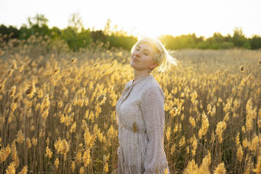 Portrait of woman standing in field at sunset - TETF02053