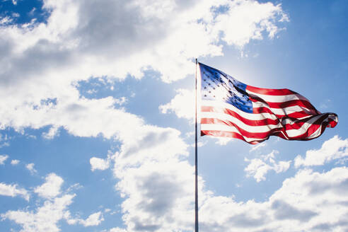 American flag blowing on wind against sky on sunny day - TETF02060