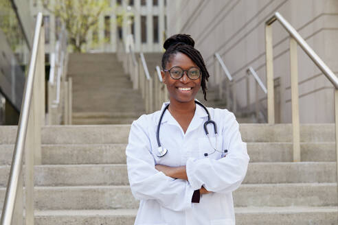 Portrait of smiling female doctor on steps in city - TETF02066