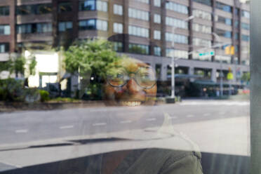 USA, New York, New York City, Smiling woman reflected in window in city - TETF02067