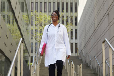 Portrait of smiling female doctor on steps in city - TETF02069